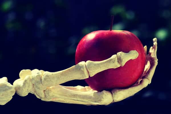 Mano de esqueleto sujetando una manzana