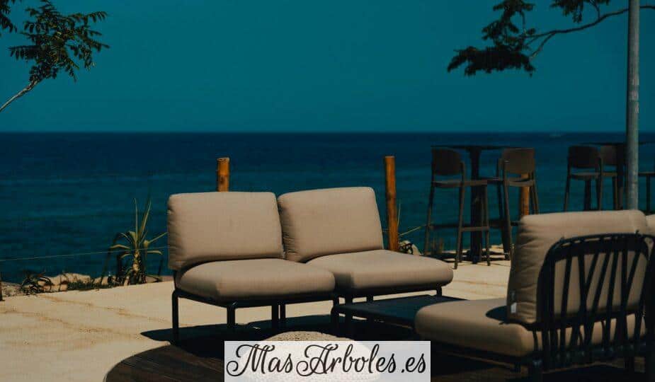 A couch and chair sitting on a patio next to the ocean